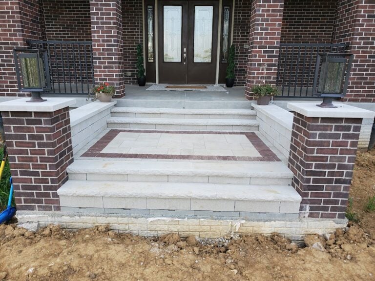 Custom stone entryway steps in Cedar Rapids, IA, featuring elegant brick pillars and integrated lighting. Professionally designed hardscape installation for a stunning and durable front entrance upgrade.