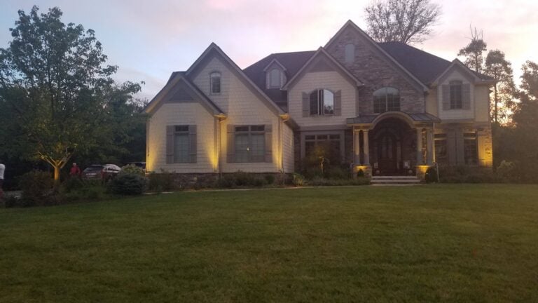 Luxury home with professional landscape lighting illuminating the front yard and architectural details. Well-manicured lawn and soft outdoor lighting enhance curb appeal and create a welcoming ambiance.