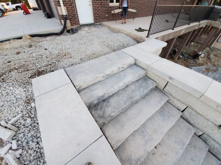 Custom limestone steps with concrete edging leading to a brick home in Cedar Rapids, IA. Professionally installed hardscape design for durability and aesthetic appeal in outdoor landscaping projects.