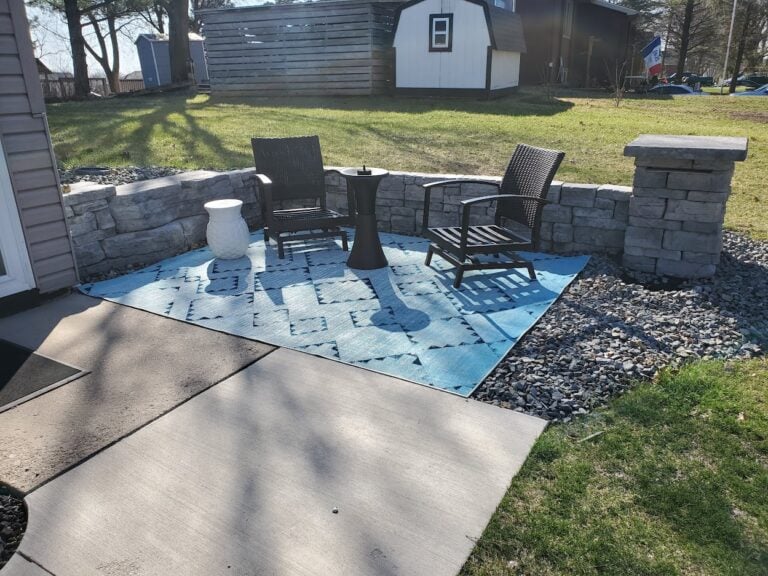 Cozy outdoor patio with a natural stone retaining wall and modern seating area. Designed for relaxation and backyard entertaining, featuring durable hardscaping elements.