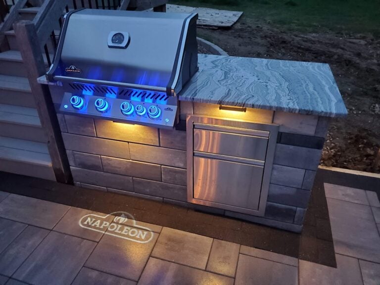 Modern outdoor kitchen with built-in Napoleon grill, LED lighting, and stone countertop. This sleek backyard BBQ setup enhances outdoor entertaining and adds luxury to patio spaces.