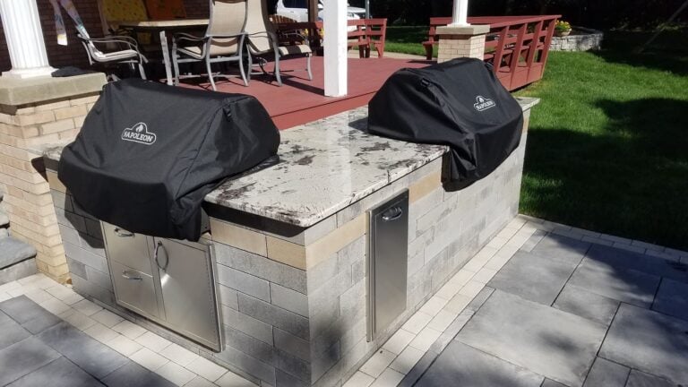 Custom outdoor kitchen with granite countertop and built-in Napoleon grills, perfect for backyard entertaining. High-end hardscaping and paver patio design for durability and style.